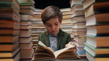 Yakışıklı küçük çocuk kütüphanede kitap sayfalarını karıştırıyor. İlkokul çocuğu kitapçıda ya da kitapçıda okumayı seviyor. Yüksek kalite 4k görüntü