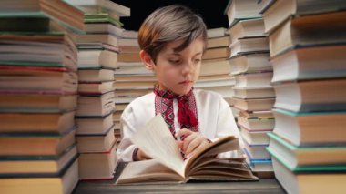 Yakışıklı küçük Ukraynalı çocuk kütüphanede kitap sayfalarını karıştırıyor. İlkokul çocuğu kitapçıda ya da kitapçıda okumayı seviyor. Yüksek kalite 4k görüntü