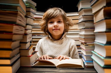 Yakışıklı küçük çocuk kütüphanede kitap sayfalarını karıştırıyor. İlkokul çocuğu kitapçıda ya da kitapçıda okumayı seviyor. Yüksek kalite