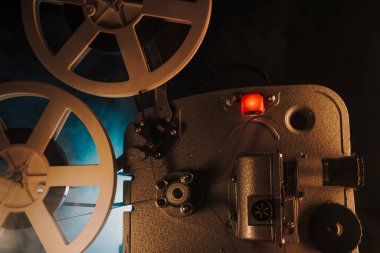Retro projektör karanlık odada film oynuyor. Eski filmlerin zamansız titreşimleri. Eski nesneler, sinema, Hollywood konsepti. Festival geçmişi ve yayın ekipmanları için mükemmel. Yüksek kalite