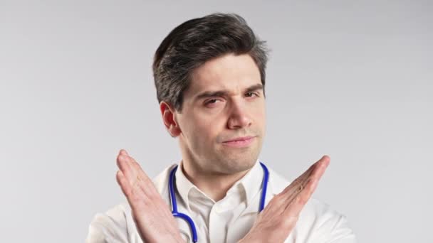 手のサインを交差させない ジェスチャーを拒否し 手のひらを止める プロの医療白いコートの深刻な医者 青い背景で孤立した男 高品質4Kについて — ストック動画