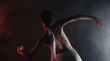 Çıplak sırtlı, muhteşem modern koreografi sergileyen muhteşem esnek bir kadın. Karanlık stüdyoda zarif bir modern tarz dansı. Serbest stil el hareketleri. Yüksek kalite 4k görüntü