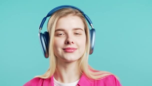 快乐的女人变得很兴奋 喜欢听音乐 喜欢在粉色工作室的背景下与耳机共舞 无线电 无线现代音响技术 在线播放器 高质量4K — 图库视频影像