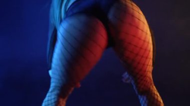 Cazibeli kadın modern dans giyer, twerk. Kız sallanıyor, poposunu sallıyor stüdyo arka planına yakın çekim yapıyor, neon ışığı yanıyor. Yavaş çekim, 4k