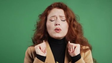 Oldukça sakin bir kadın yeşil stüdyoda meditasyon yapıyor. Bayan stresi reddediyor ve durumu kabulleniyor, sakinleşiyor, derin nefes alıyor. Yoga, zen, sağlık yaşam tarzı konsepti. Yüksek kalite 4k görüntü