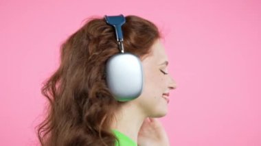 Mutlu kadın kafayı bulur, müzik dinler, pembe stüdyo arka planında kulaklıklarla dans etmekten zevk alır. Radyo, kablosuz modern ses teknolojisi, çevrimiçi çalar. Yüksek kalite 4k