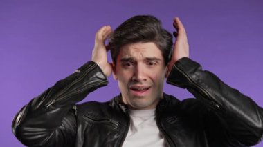 Şok olmuş korkmuş bir adam bir şeyden korkuyor ve mor arka plandaki büyük gözlerle kameraya bakıyor. Fobi, sorun, panik konsepti. Yüksek kalite 4k