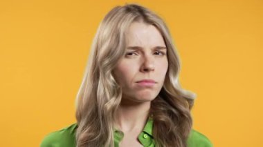 Ciddi bir kadın baş işareti olmadan onaylamıyor, onaylanmayacak şekilde başını sallıyor. Reddetmek, reddetmek, anlaşmazlık, sarı arka planda güzel bir bayanın portresi. Yüksek kalite 4k görüntü