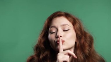 Gülümseyen kızıl saçlı, dudak tutan, yeşil stüdyo geçmişi olan bir kadın. Şşş, sır, sessizlik, komplo, dedikodu konsepti olan hoş bir bayan. Yüksek kalite 4k