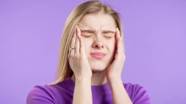 Acı çeken güzel bir kadının portresi baş ağrısı, menekşe stüdyo portresi. Ellerini başının üstüne koyan bir kız. Migren sorunları, ilaç, hastalık, manyetik fırtınalar kavramı. 4k