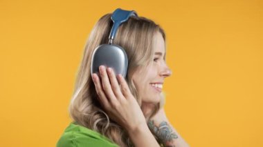 Mutlu kadın kafayı bulur, müzik dinler, sarı stüdyo arka planında kulaklıklarla dans etmekten zevk alır. Radyo, kablosuz modern ses teknolojisi, çevrimiçi çalar. Yüksek kalite 4k