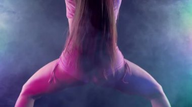 Cazibeli kadın modern dans giyer, twerk. Kız sallanıyor, poposunu sallıyor stüdyo arka planına yakın çekim yapıyor, neon ışığı yanıyor. Yavaş çekim, 4k