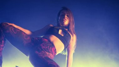 Seksi kadın yerde vücuduyla esnek hareketler yapıyor. Baştan çıkarıcı ateşli kafa, titreyen saçlar, neon ışıkla stüdyoda dans etmek. Dar elbiseli ve topuklu ayakkabılı bayan dansçı. Yüksek kalite 4k görüntü