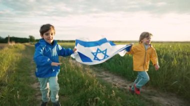 Mutlu İsrail Yahudi çocukları İsrail bayrağıyla koşuyor. Bağımsızlık Günü. Vatanseverlik. Vatansever çocuklar, açık alanda arkadaşlar. Demokrasinin, bağımsızlığın ve geleceğin sembolü. Yüksek kalite 4k