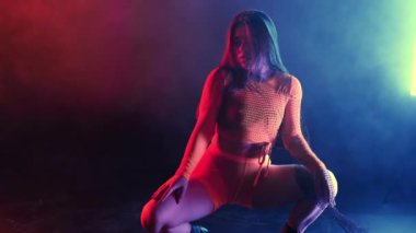Seksi koreografi, kadın neon dar kostümle seksi hareketler sergiliyor. Çok renkli ışık stüdyosunda baştan çıkarıcı dans. Duman içindeki bayan dansçı. Yüksek kalite 4k görüntü