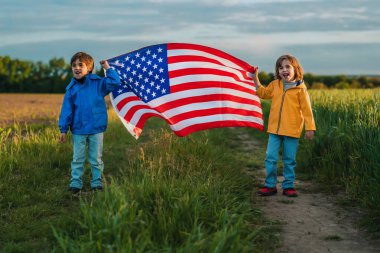 Sevimli erkek çocuklar, erkek kardeşler, açık alanda ulusal bayrak taşıyan Amerikan vatansever çocuklar. ABD, 4 Temmuz Bağımsızlık Günü, kutlamalar. ABD, Gaziler, seçimler, Amerika, işçiler