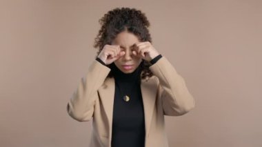 Genç, güzel Afrikalı bir kız gözlerini ovuşturuyor, akranları bej rengi kameraya daha yakından gülümsüyor, inanılmaz bir haber, sürpriz. Yüksek kalite 4k görüntü