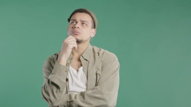 Hipster Afro-Amerikan 'ın çevresini yeşile boyadığını düşünmekten. Kafası karışmış öğrencinin cevabı bulması ya da ne unuttuğunu hatırlamaya çalışması. Hafıza kavramı. Yüksek kalite 4k