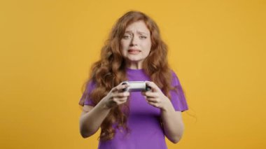 Güzelim kızıl saçlı Amerikalı kadın TV 'de heyecanlı video oyunu oynuyor. Oyun alanı sarı stüdyo arka planında izole edilmiş. Modern teknolojiyi kullanarak. E-spor, hobi, akış