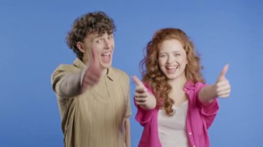 Havalı bir kadın ve el işareti olan bir erkek, iyi niyet göstergesi. Mutlu çift, doğru seçim, harika anlaşma, menekşe arkaplan. Pozitif arkadaşlar kameraya gülümser, onay, güven konsepti. 4k