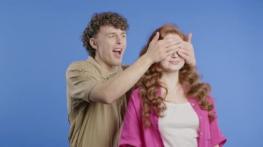 Yakışıklı Adam Sürprizden Önce Sevgili Kız Arkadaşının Gözlerini Kapar. Violet stüdyosundaki birkaç kişi. Aşk, tatil, mutluluk konsepti. Yüksek kalite 4k