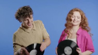 Modaya uygun bir çift, erkek ve kadın menekşe üzerinde plak plaklarıyla dans ediyorlar. Hobi, müzik aşığı, koleksiyon, nostalji yaşam tarzı. Yüksek kalite 4k görüntü
