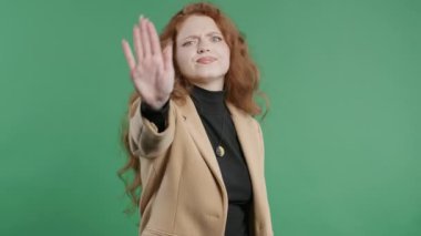 Dur işaretini tasvip etmeyen stil düşkünü genç bir bayan öğrenci. Benimle oynama, bu kadar yeter. Yeşil arka planda bayan portresi. Yüksek kalite 4k