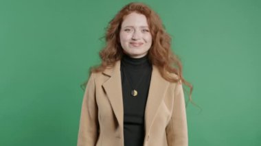 İş ceketi giymiş güzel bir kadın evet işareti veriyor, başını sallıyor, onaylıyor. Olumlu gülümseyen Avrupalı kadın, vücut dili. Doğru mükemmel seçim, harika bir anlaşma. Yeşil stüdyo geçmişi.