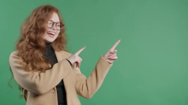 Gülümseyen 30 'lu yaşlardaki öğrenci bayan reklamınız için boş bir yer arıyor. Önerilen kadın sağ tarafı işaret ediyor, boşluğu kopyalayın. Kadın, yeşil arka planda izole edilmiş bir şey sunuyor. Yüksek kalite