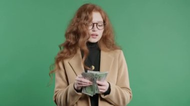 Nakit parası olan zengin bir iş kadını. Yeşil duvardaki Amerikan doları banknotları. İkramiye, kazanç, zafer, kazanan piyango, maaş sembolü. Yüksek kalite 4k