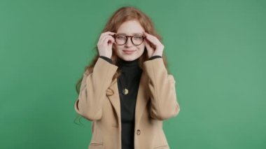 Çekici bir kadın gözlük takar, saçını yaptırır, doğal güzelliğini takar. Yeşil stüdyoda genç bir iş kadını ya da öğrenci portresi. Yüksek kalite 4k görüntü