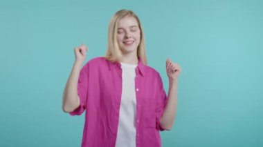 Fuşya gömlekli neşeli, genç bir kadın. Eğleniyor, müzik dinliyor, gülümsüyor, mavi stüdyo arka planında dans ediyor. Müzik, dans konsepti, 4k