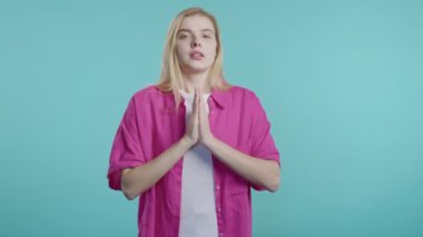 Genç bir kadın dua ediyor, özür diliyor, o suçlu. Mavi arka plan. Umut dolu dua eden kız, birinden arzularını tatmin etmesini ister, yardım ister. Yüksek kalite 4k