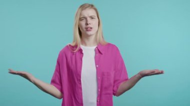 Sinirli bir kadın kamerayı işaret ediyor ve nasıl bir jest yaptığını gösteriyor. Deli misin diye soruyorum. Kavgacı kadın mavi arka planda izole edilmiş. Öfkeli ifade, birini suçlamak..