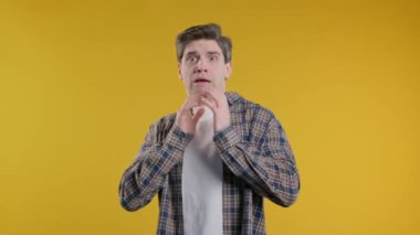 Şok olmuş korkmuş bir adam bir şeyden korkuyor ve sarı arka planda korku dolu büyük gözlerle kameraya bakıyor. Fobi, sorun, panik konsepti. Yüksek kalite 4k
