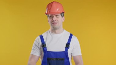 Koruyucu üniformalı ve kasklı hayal kırıklığına uğramış tamirci facepalm yapıyor. Pişmanlık, başarısızlık, tatminsizlik, zaman kaybı, inşaat alanında sorunlar, sarı stüdyo geçmişi. Yüksek kalite 4k