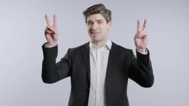 30 'lu yaşlarda resmi giyinmiş bir iş adamı. İki parmak tırnak işareti, beyaz, iğneleme. Hiç komik değil. Yüksek kalite 4k görüntü