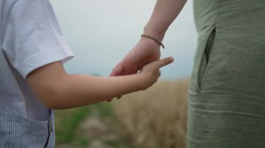Anne ve çocuğun el ele tutuşması, aile geçmişi. Oğul, Anne Eli Tutar. Güven, aşk ve mutluluk kavramı. Doğanın kırsal kesiminde yürüyorum. Yüksek kalite 4k görüntü