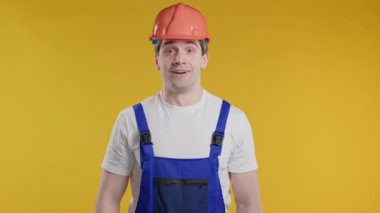 Beyaz yakışıklı işçi ya da inşaatçı şok olmuş, sevinmiş, çığlık atıyormuş. İlgi çekmeye çalışan etkileyici bir adam. Kârlı teklif kavramı. Sarı arka plandaki heyecanlı, mutlu tamirci. Yüksek kalite 4k