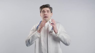 Beyaz önlüklü korkmuş bir doktor bir şeyden korkar ve beyaz arka planda korku dolu büyük gözlerle kameraya bakar. Fobi, sorun, panik konsepti. Yüksek kalite 4k