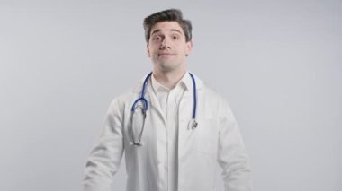 30 'lu yaşlarda beyaz önlüklü bir doktor iki parmağıyla beyaz tırnak işareti yapıyor. İğneleme. Hiç komik değil. Yüksek kalite 4k görüntü