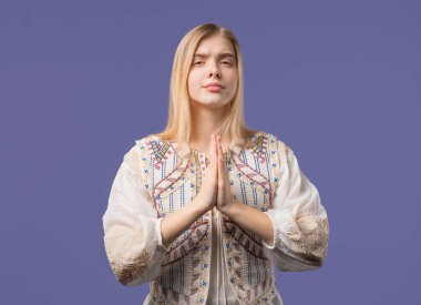 Genç bir kadın dua ediyor, özür diliyor, o suçlu. Menekşe arkaplan. Umut dolu dua eden kız, birinden arzularını tatmin etmesini ister, yardım ister. Yüksek kalite