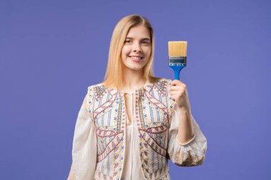 Violet 'in arka planında fırçası olan genç bir kadın sanatçı. Yaratıcı kişi, fantezi, fikir, hayata standart olmayan yaklaşım. Yüksek kalite fotoğraf