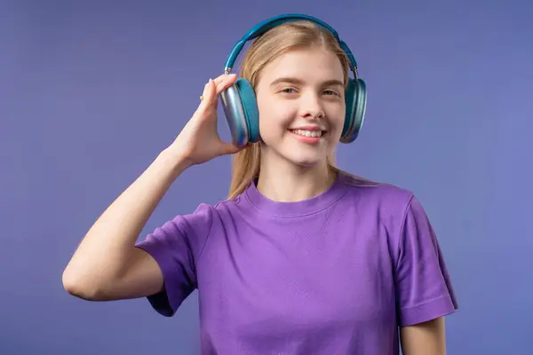 stock image Happy woman gets high, listening music, enjoying dance with headphones on Violet studio backdrop. Radio, wireless modern sound technology, online player. High quality