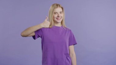 El işaretli şık bir kadın, baş parmak işareti gibi. Mutlu bayan, doğru seçim, harika bir anlaşma, menekşe arkaplan. Pozitif kadın model kameraya gülümser, onay, güven konsepti. kalite 4k