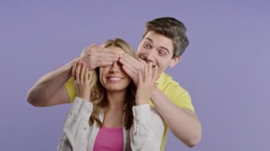 Yakışıklı Adam Sürprizden Önce Sevgili Kız Arkadaşının Gözlerini Kapar. Violet stüdyosundaki birkaç kişi. Aşk, tatil, mutluluk konsepti. Yüksek kalite 4k
