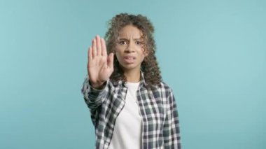 İlgisiz stil düşkünü Afro-Amerikan genci dur işaretini onaylamıyor. Benimle oynama, bu kadar yeter. Mavi arka planda bayan portresi. Yüksek kalite 4k