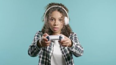 Televizyonda video oyunu oynayan genç ve güzel bir kız mavi stüdyo arka planında joystick izole edilmiş. Modern teknolojiyi kullanarak. E-spor, hobi, akış