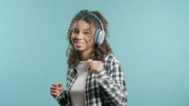 Mutlu genç kız kafayı bulur, müzik dinler, mavi stüdyo arka planında kulaklıklarla dans etmekten zevk alır. Radyo, kablosuz modern ses teknolojisi, çevrimiçi çalar. Yüksek kalite 4k