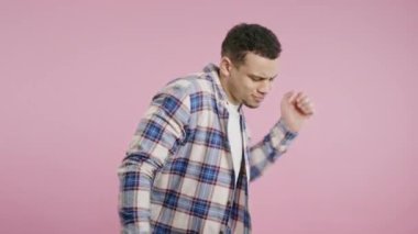 Müzik dinleyen, pembe stüdyo arka planında dans eden Afro-Amerikan bir adam. Radyo, kablosuz modern ses teknolojisi, çevrimiçi çalar. Yüksek kalite 4k